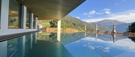 Una piscina al aire libre, sombrillas, sillones reclinables de piscina