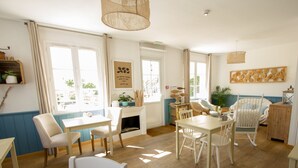 A bright, well-lit room with a wooden floor, white furniture, and large windows allowing natural light.