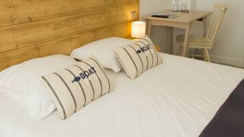 A neatly made bed with two pillows labeled "Boat No 59" and a wooden headboard.