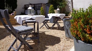 An outdoor seating area with tables and chairs, surrounded by gravel and plants.