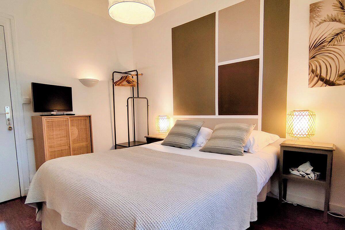 A bedroom with a large bed, a television, a wardrobe, and two bedside lamps.