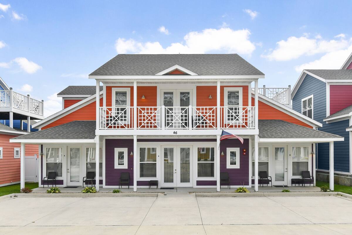 A two-story building with a balcony, a front porch, and a flag.