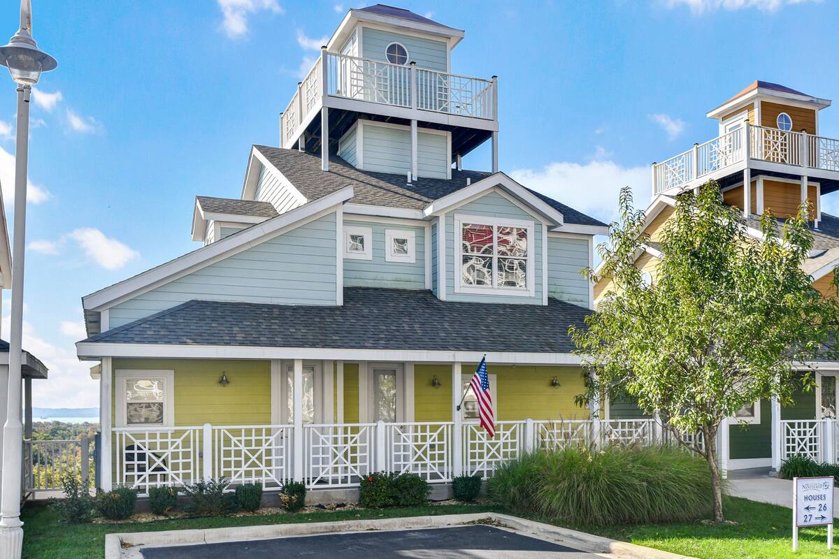 A two-story house with a balcony, a small tower-like structure on the roof, and a sign indicating the house number.