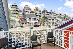 A colorful row of beach houses with a wooden deck and wicker chairs.