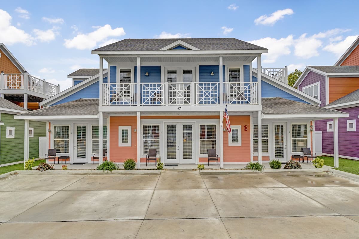 A two-story residential building with a balcony, a front porch, and a driveway.