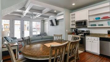 A modern kitchen with white cabinetry, a built-in microwave, and a dining area with a wooden table and chairs.