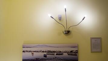 A wall-mounted light fixture with three bulbs and a framed picture of boats on water.