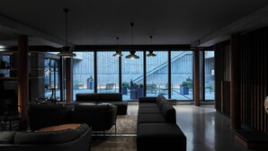 A modern interior with a sectional sofa, a dining area, and large windows offering a view of an outdoor staircase. - Exeter Hotel (Reykjavik)