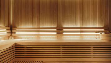 A sauna with wooden slats and benches, a wooden bench, and a small wooden table.