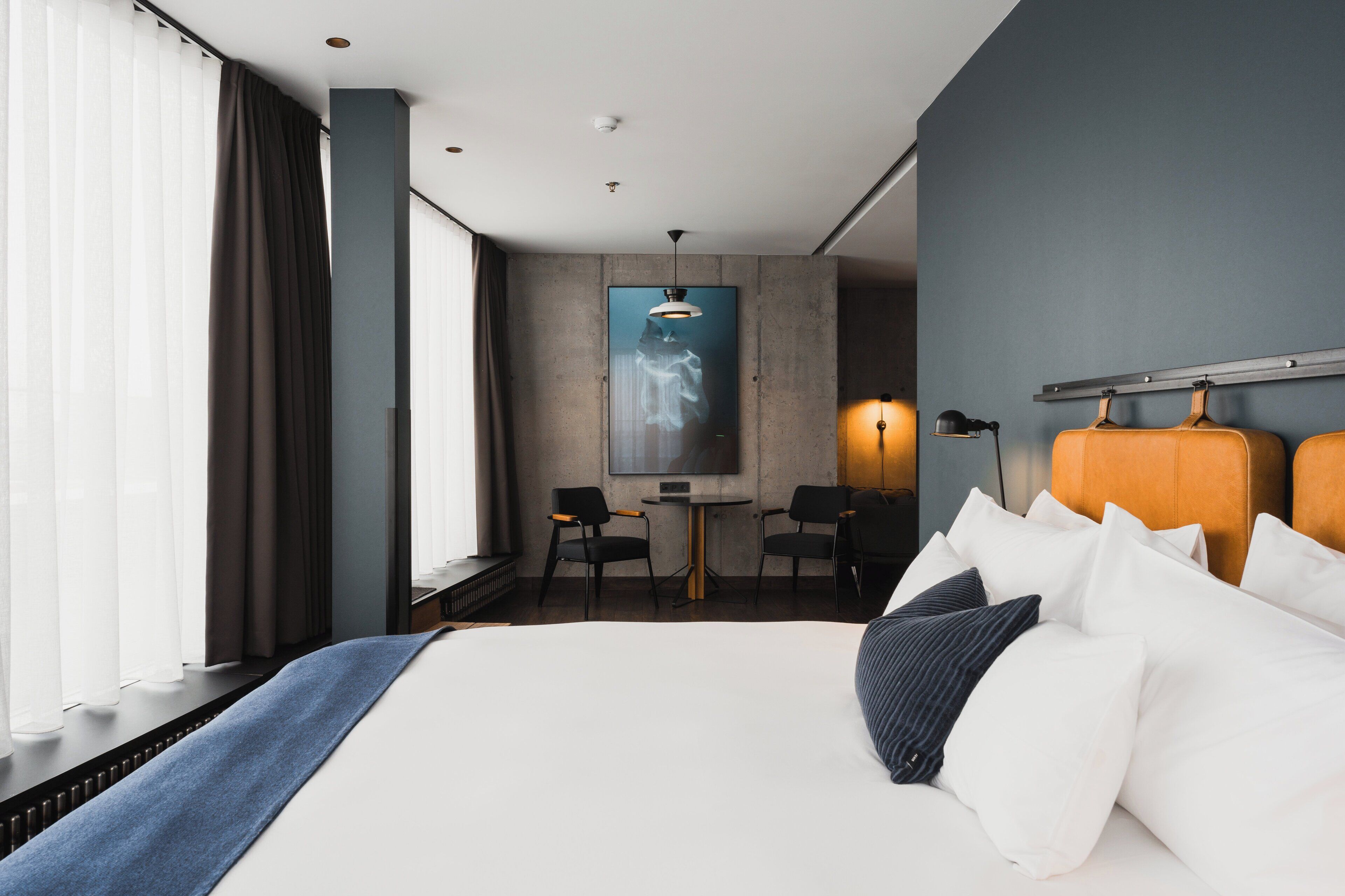 A modern hotel room with a large bed, a desk, and a chair.