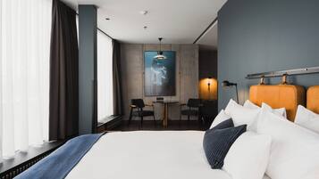 A modern hotel room with a large bed, a desk, and a chair.