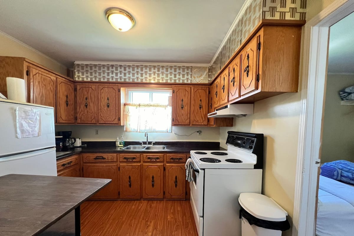 A compact kitchen with wooden cabinets, a white stove, and a sink.