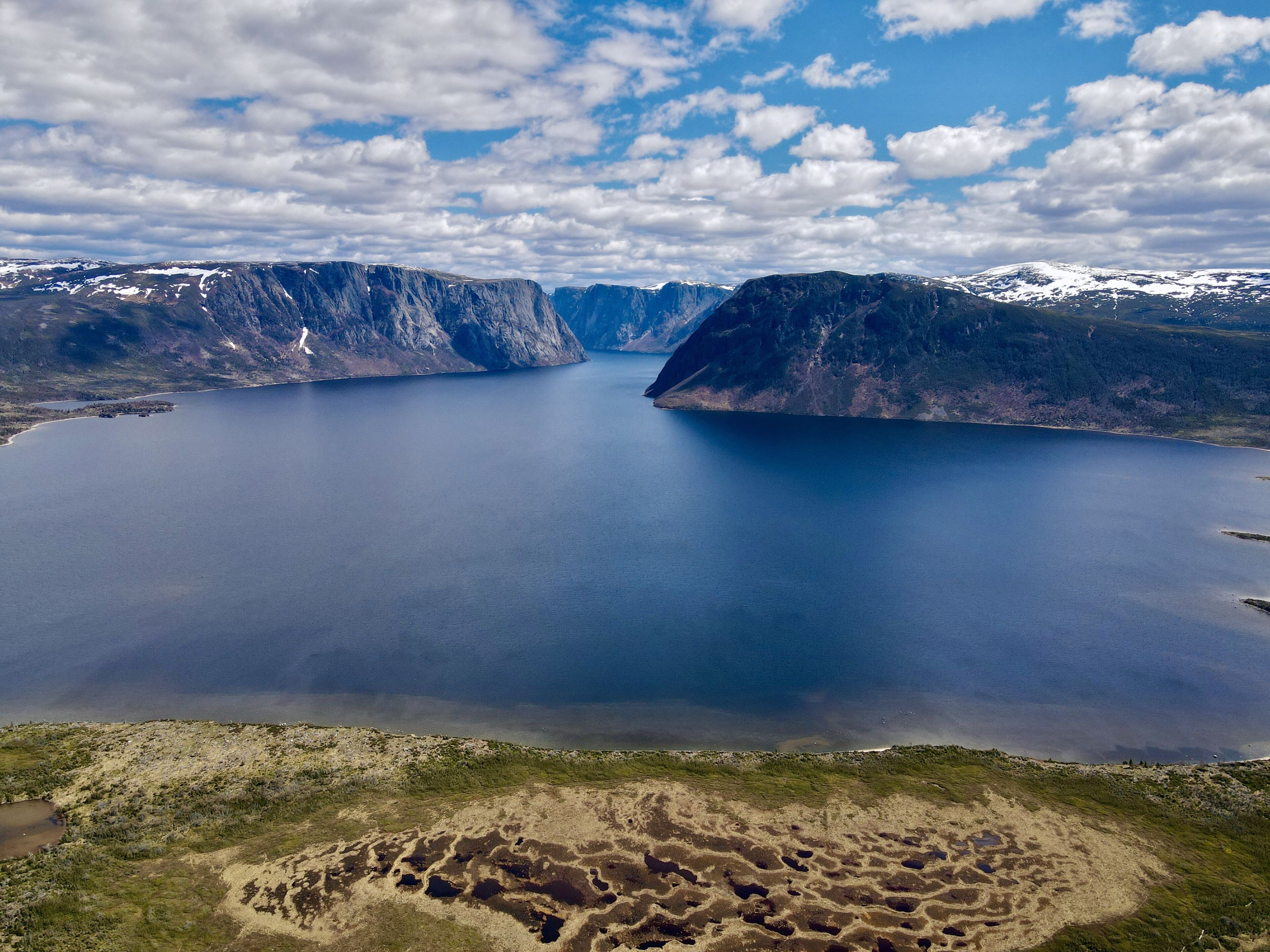 A large body of water surrounded by mountains with a clear sky.