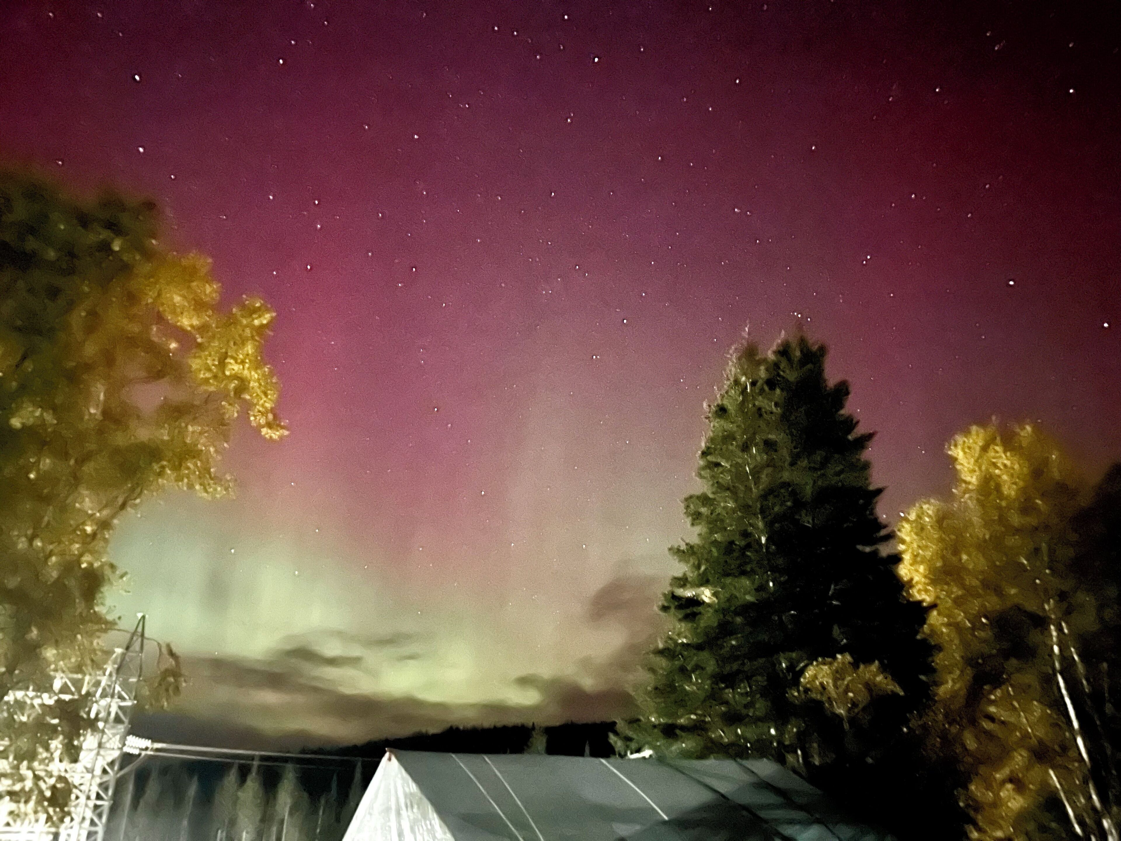 A tent under a starry sky with a visible aurora.