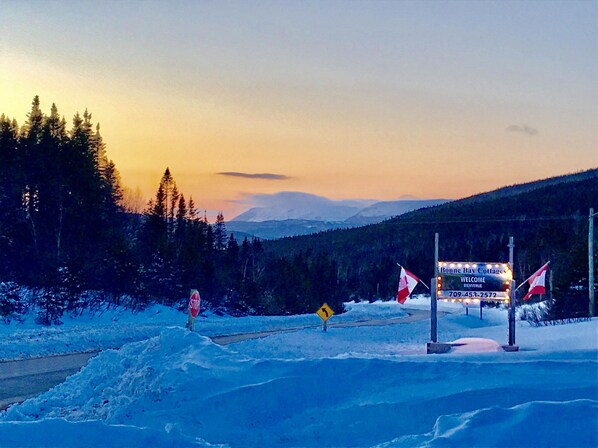 A snowy landscape with a sign for Bonne Bay Cottages.