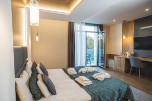 Una habitación de hotel moderna con una cama grande, un escritorio, una silla y un televisor.