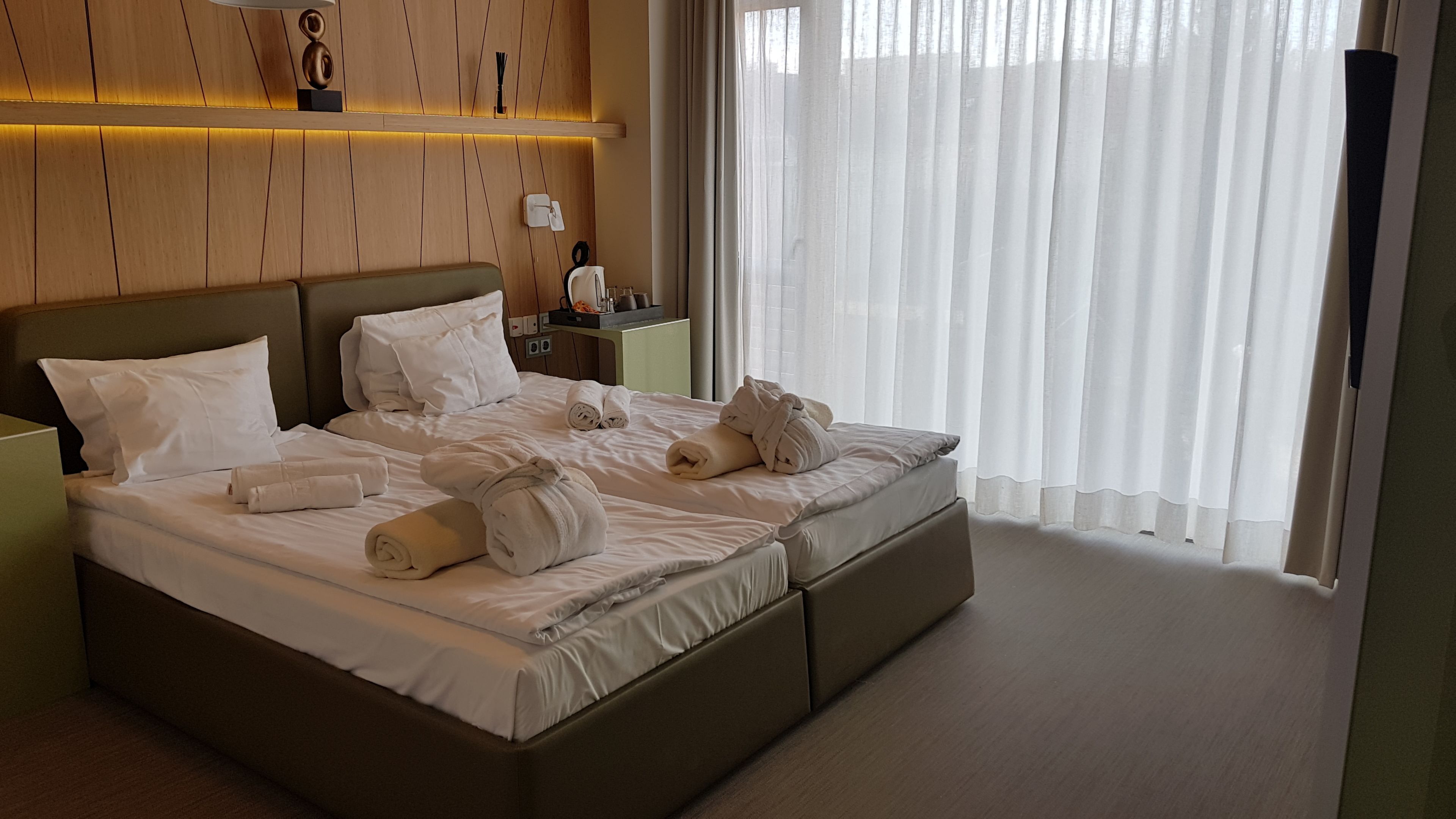 Ein Hotelzimmer mit einem großen Bett, weißen Leinentüchern und ordentlich gefalteten Handtüchern.