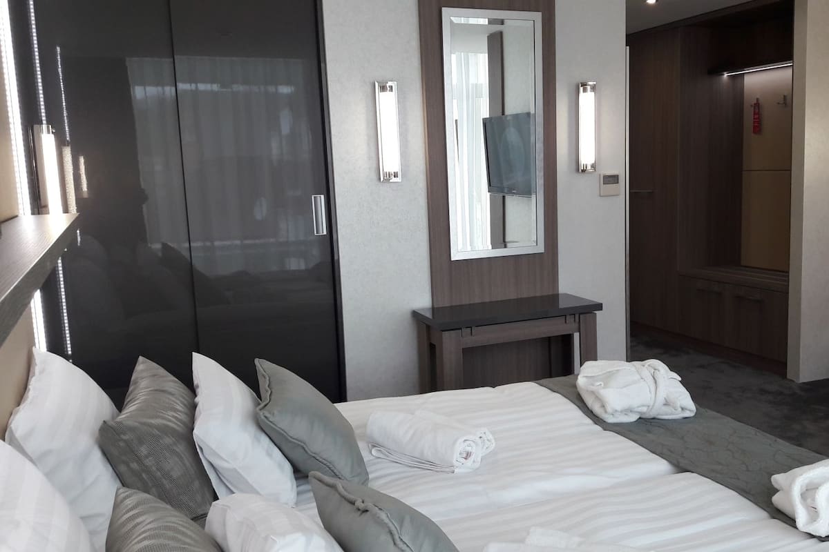 Ein Hotelzimmer mit Bett, Nachttisch, Spiegel, Kleiderschrank und Fernseher.