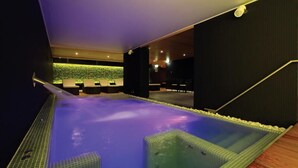 A spa area with a heated pool, seating area, and a wall with greenery. - Hotel ZENA beauty & shopping center (Hévíz)