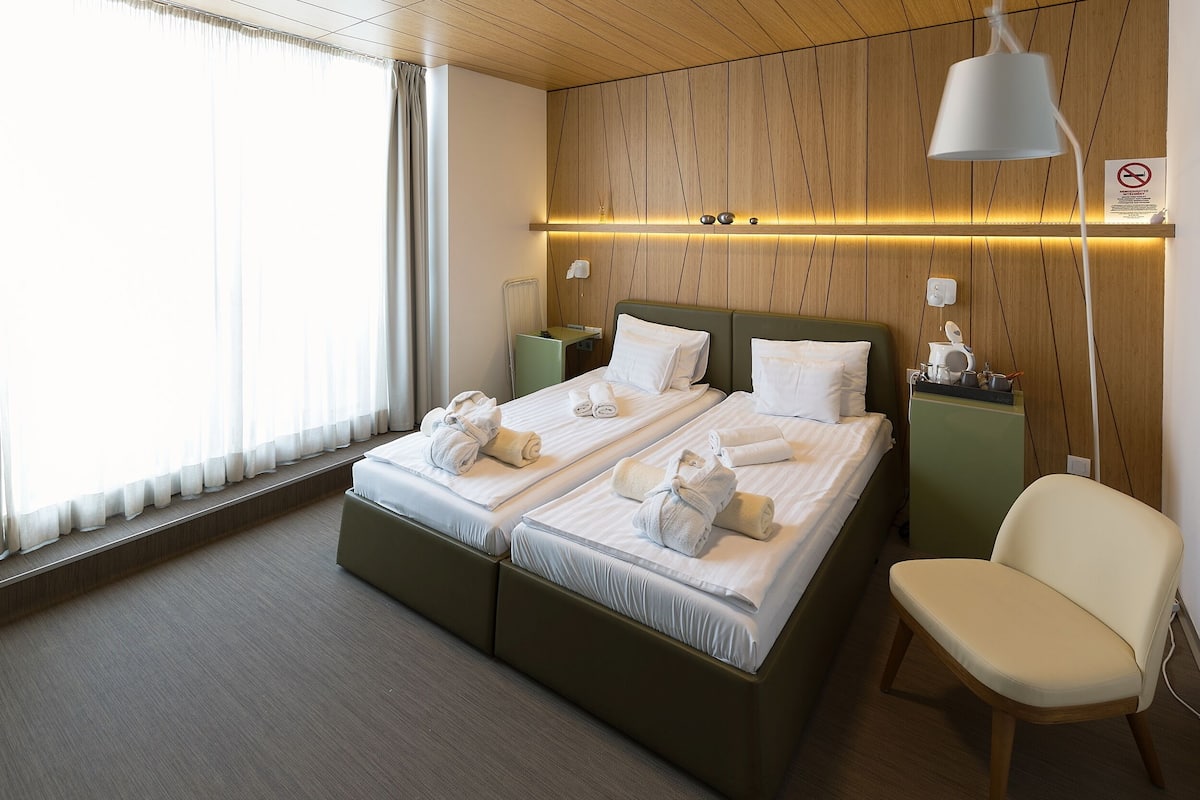 Ein Doppelbett mit weißen Bettwäsche und Handtüchern, ein Nachttisch, ein Stuhl und eine Wandlampe.