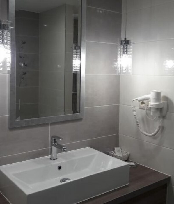 Un baño con un lavamanos rectangular, un espejo y un perchero para toallas.