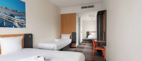 Habitación de hotel con dos camas, un escritorio, una silla, un ventanal grande y un cuadro en la pared.
