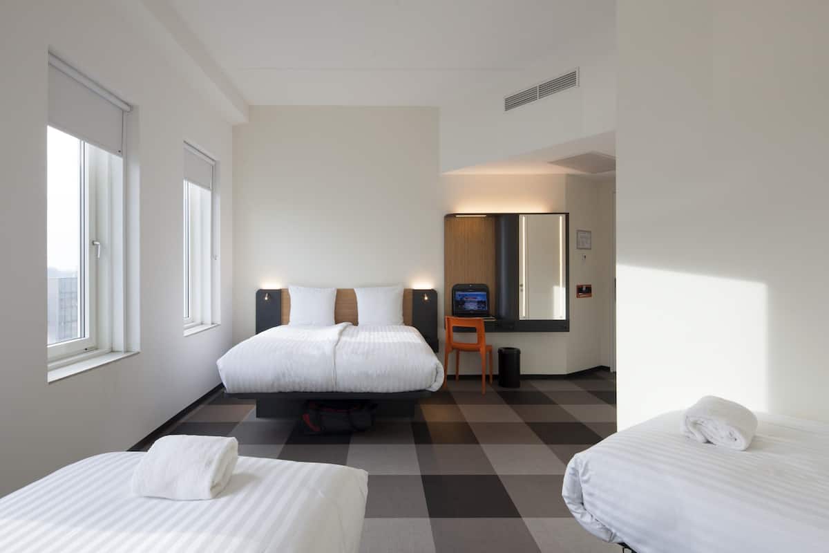 Een hotelkamer met twee bedden, een bureau, een stoel en een televisie.