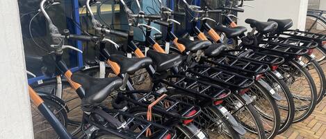 A row of bicycles parked outside a building with a blue door and a glass entrance.