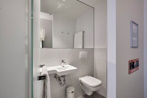 A modern bathroom with a glass shower enclosure, a white sink, and a toilet. - easyHotel The Hague Scheveningen Beach (The Hague)