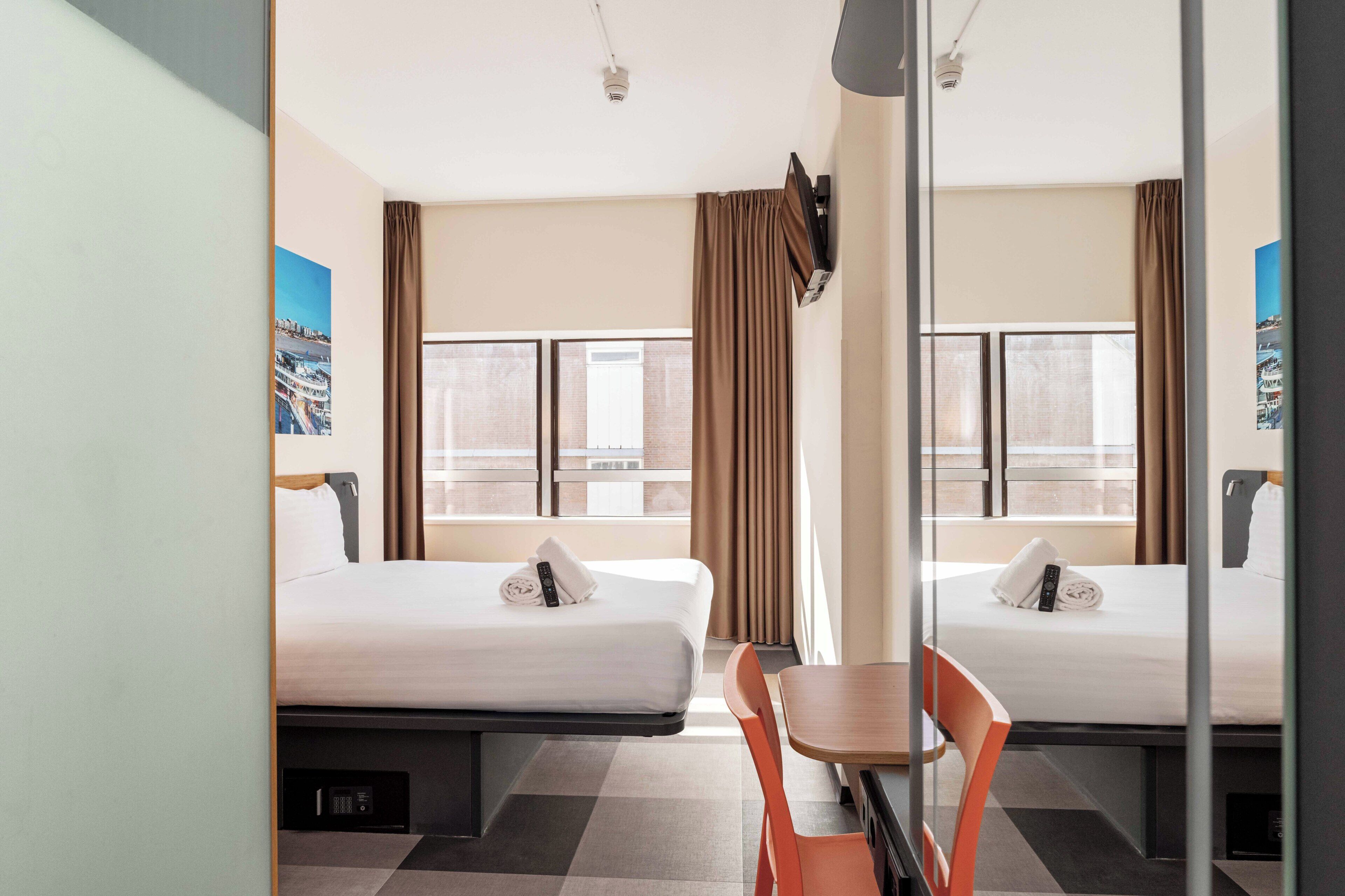 Een hotelkamer met twee bedden, een tafel en een stoel.