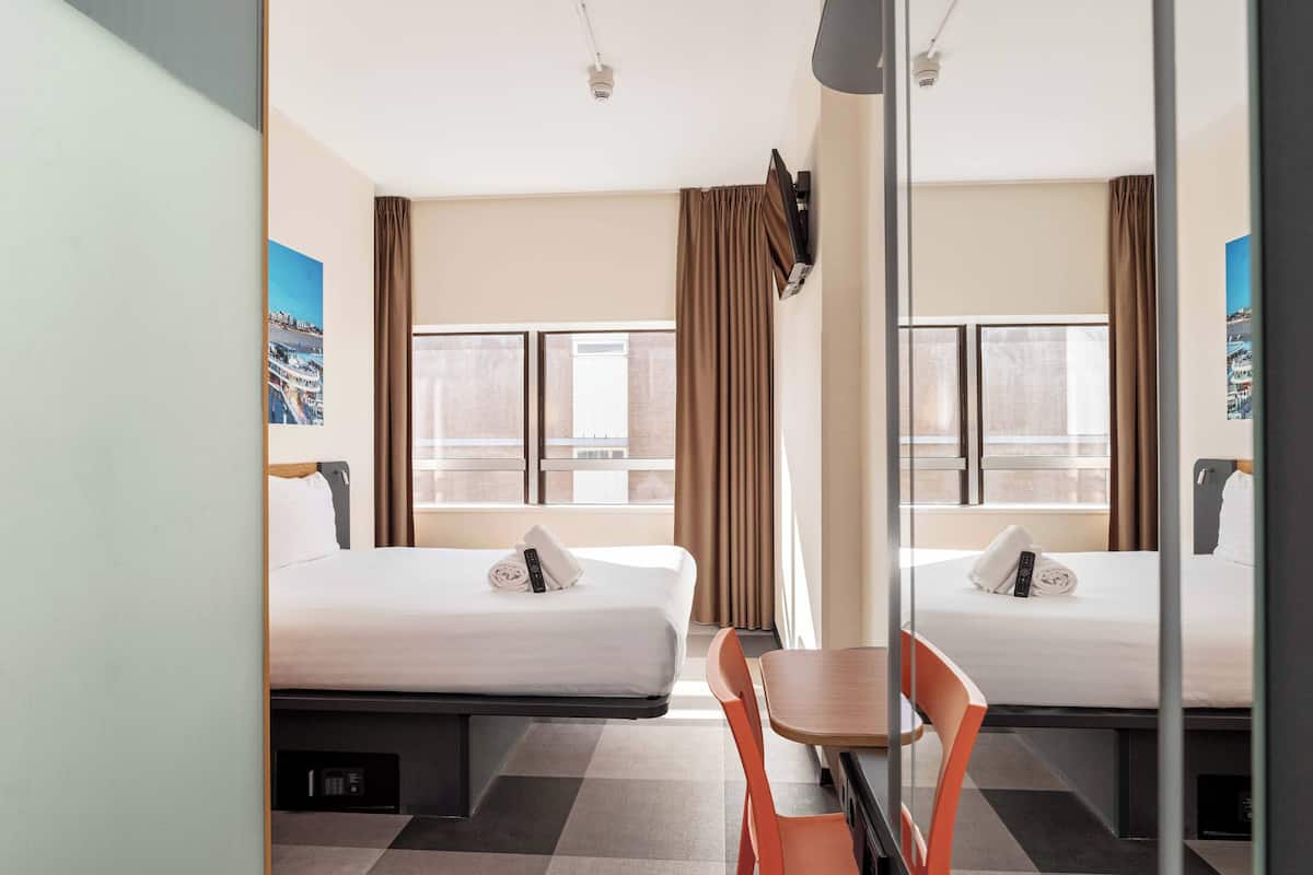 Een hotelkamer met twee bedden, een tafel en een stoel.