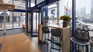 Een moderne receptie met een houten toonbank, twee zwarte kuipstoelen en een laptop.