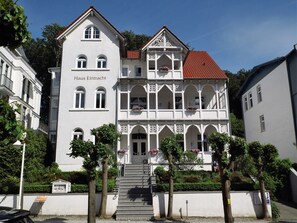 A two-story building with a white facade, a red-tiled roof, and a balcony with flower boxes. - Fewo 09 - Apartments Haus Eintracht / J. u.G. Gottschalk GbR (Sellin)