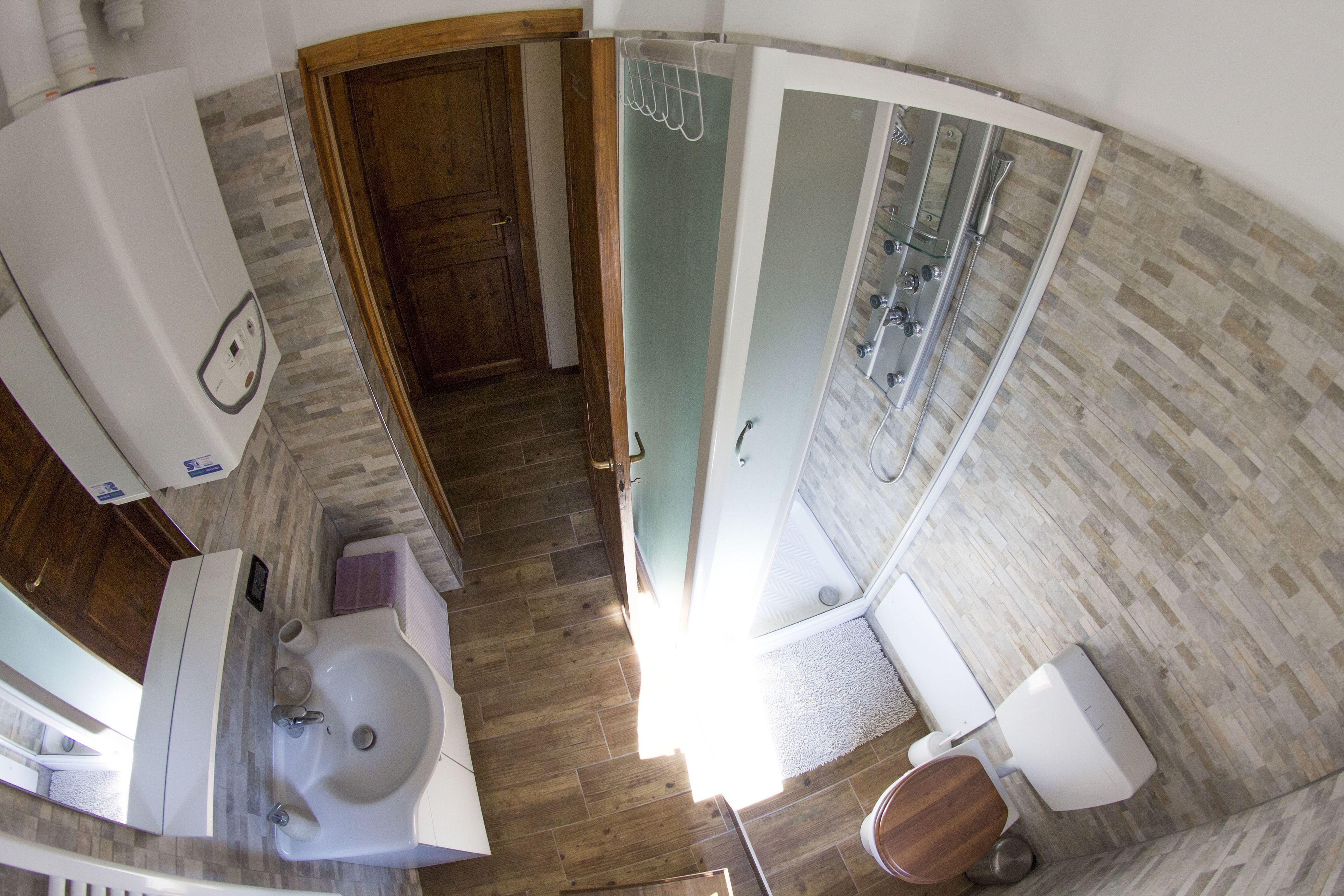 Un bagno con pavimento in legno, lavandino, WC e zona doccia.