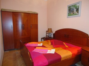A bedroom with a wooden bed, a nightstand with a lamp, and a wardrobe. - Albatros (Tbilisi)