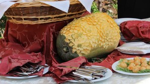 A table with a basket of bread, a carved pumpkin, and plates of food.