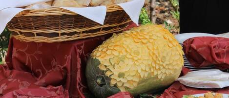 A table with a basket of bread, a carved pumpkin, and plates of food.