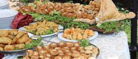A buffet table with various food items, including pastries and sandwiches, arranged on a tablecloth.