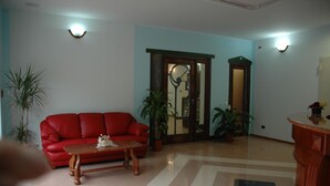 A living room with a red sofa, a wooden coffee table, and two potted plants.