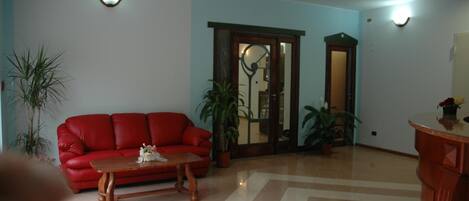 A living room with a red sofa, a wooden coffee table, and two potted plants.