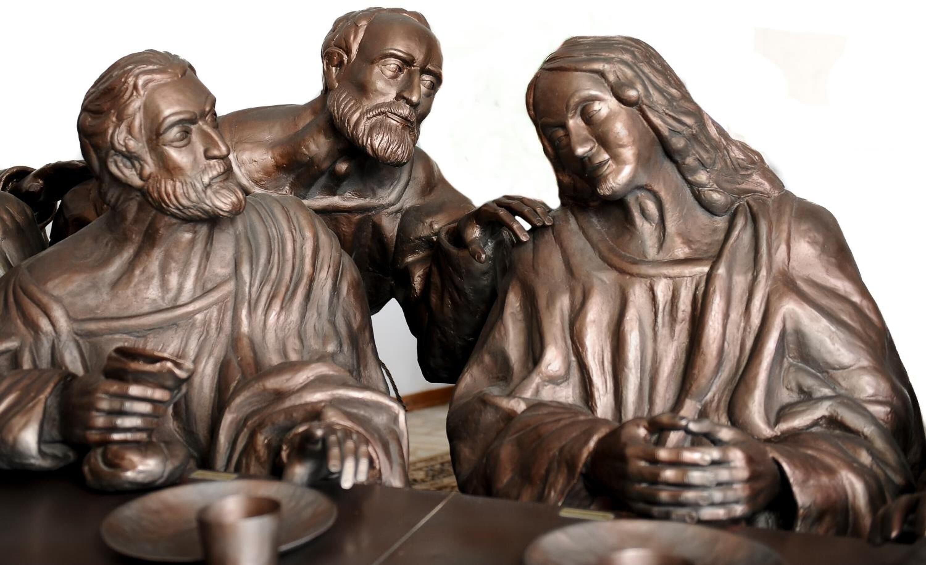 Une sculpture représentant trois personnages assis autour d’une table.