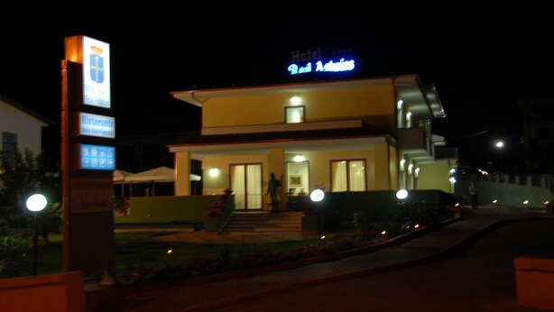 A hotel with a modern design, featuring a prominent signboard and a well-lit entrance.