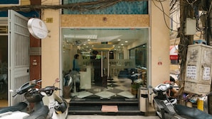 A hotel entrance with a glass door, a signboard, and two parked scooters. - Hanoi Prime Center Hotel (Hanoi)