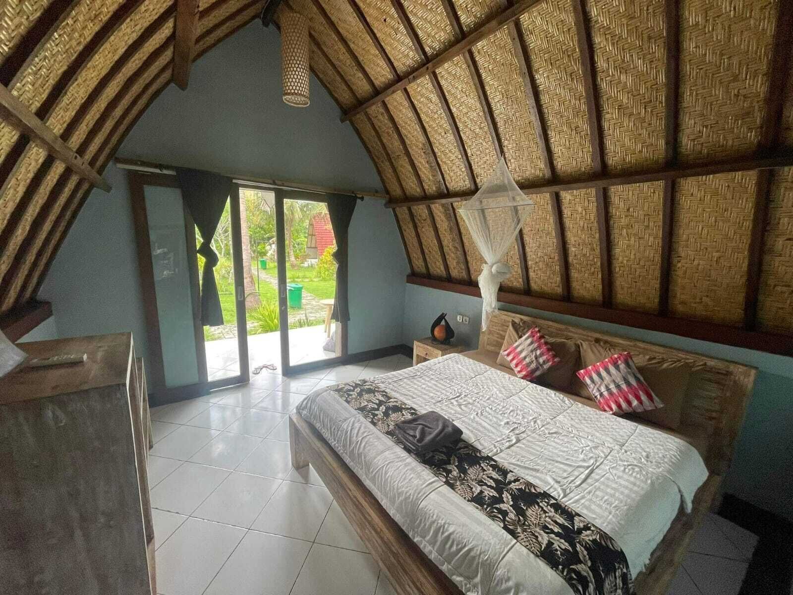 A bedroom with a large bed, a canopy bed, and a view of the outside.