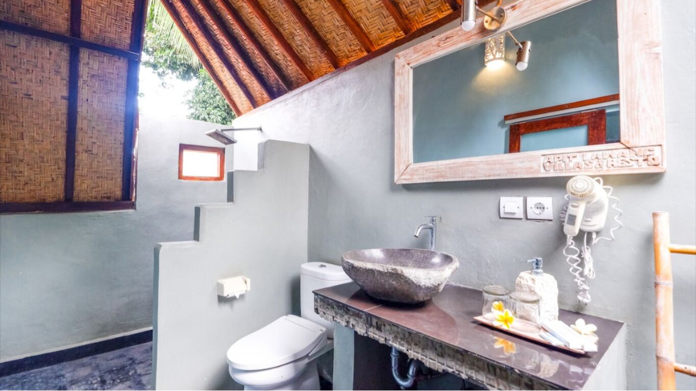 Een badkamer met een stenen wastafel, toilet, spiegel en telefoon.