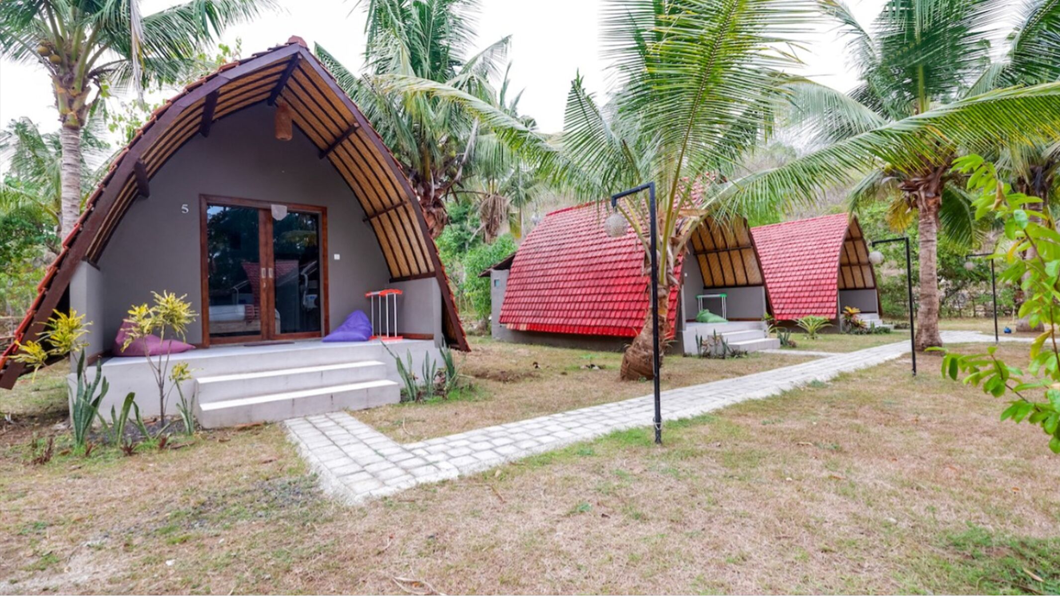 A bungalow with a sloped roof, a porch with steps, and a small table and chair set outside.