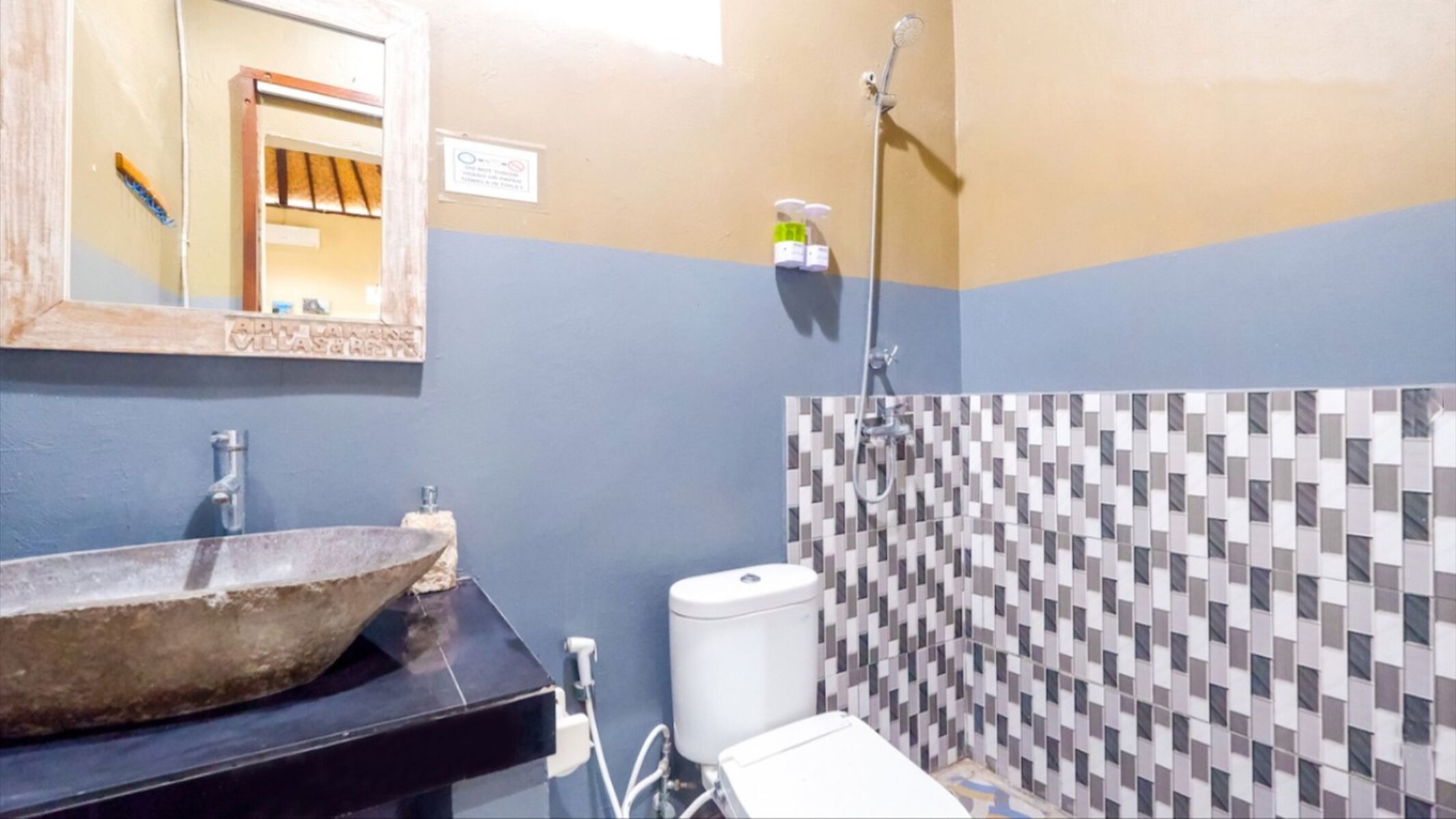 A bathroom with a large basin, a toilet, a shower, and a tiled wall.