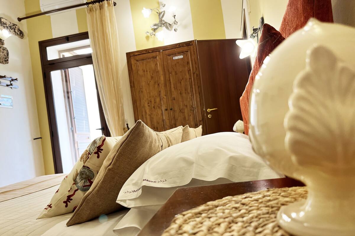 Une chambre d’hôtel avec un lit, des oreillers, une armoire en bois et une applique murale décorative.
