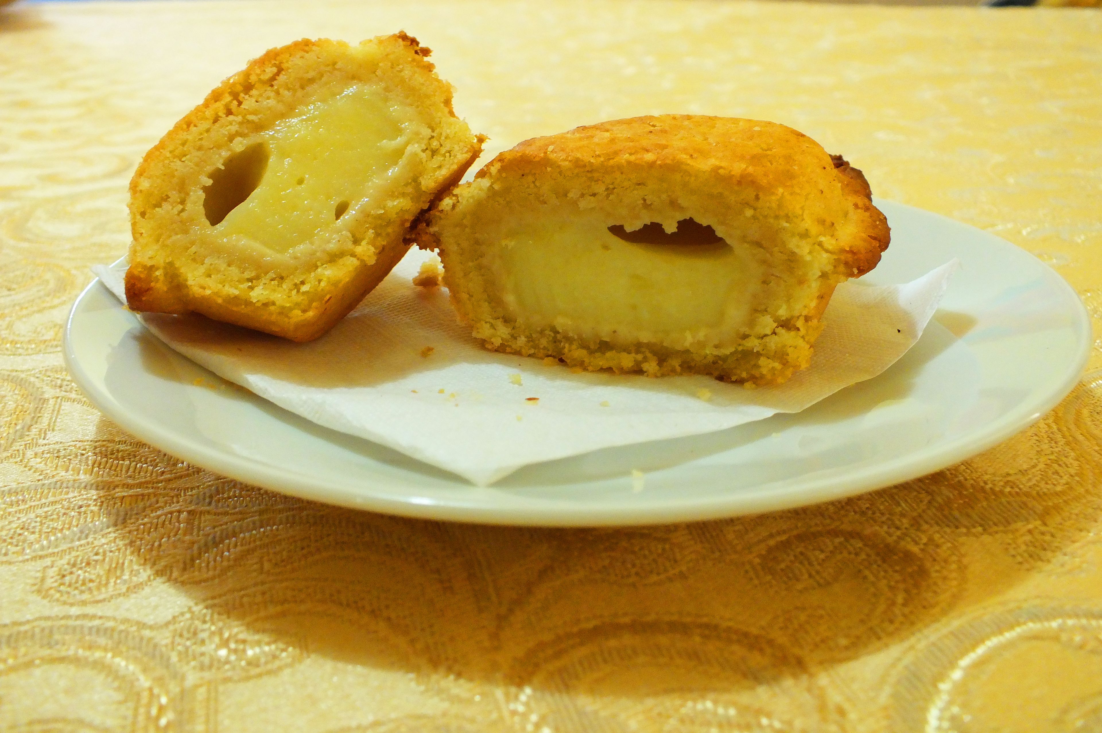 A plate with a pastry cut in half, revealing a creamy filling.