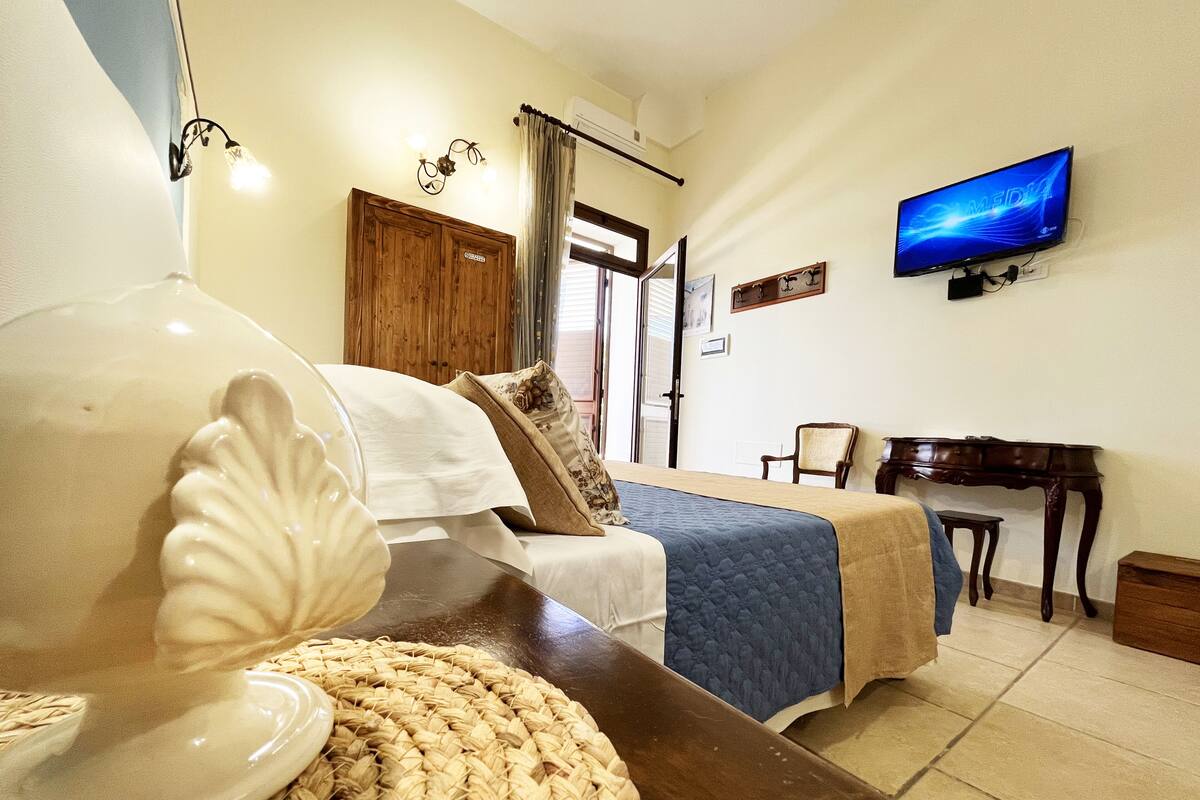 Une chambre à coucher comprenant un lit, un bureau, une télévision et une armoire en bois.